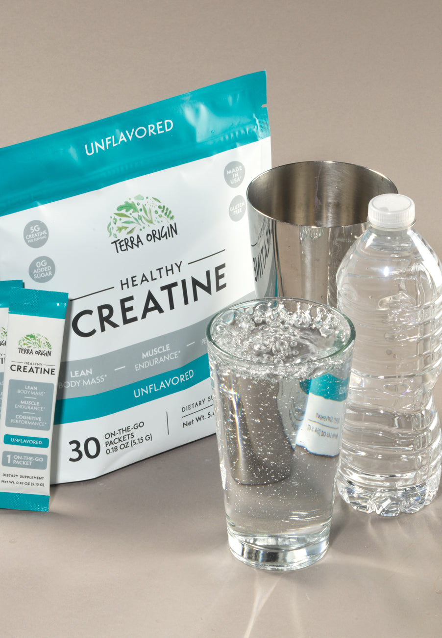 Terra Origin Healthy Creatine packaging with a glass of water and measuring cup on a neutral background