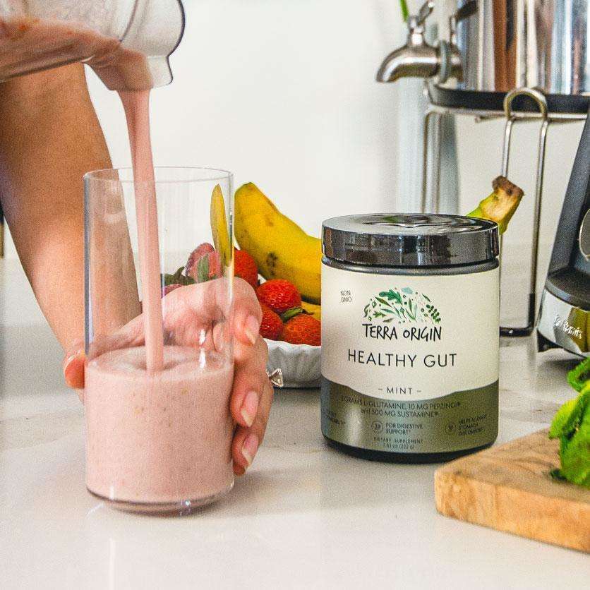 Woman making a smoothie with Healthy Gut Health Powder in a kitchen setting