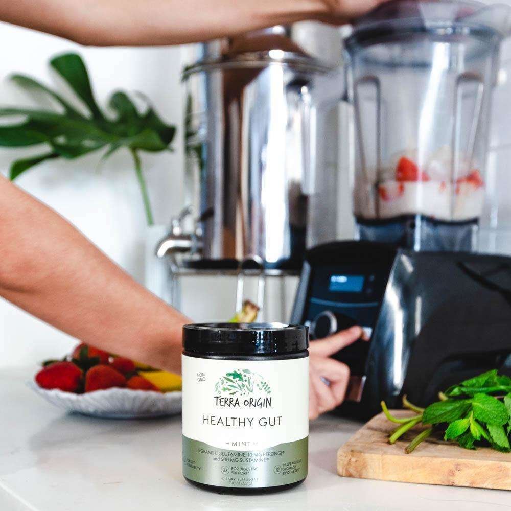 Woman making a smoothie with Healthy Gut Health Powder in a kitchen setting