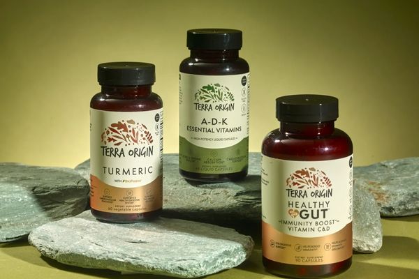 Three bottles of Terra Origin supplements on a stone surface with a yellow background