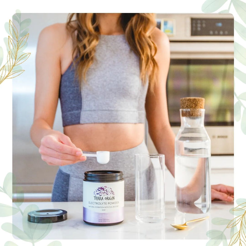 Person preparing a drink with a container of Electrolyte Powder in a kitchen setting.