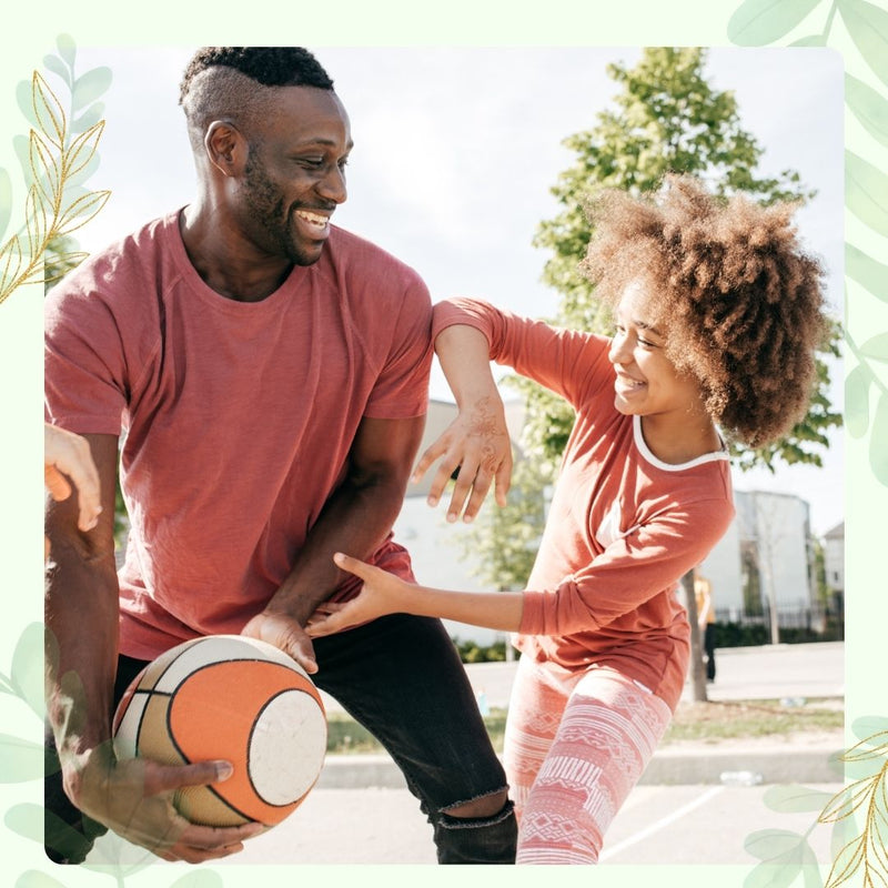 Father playing basketball outside with his young daughter