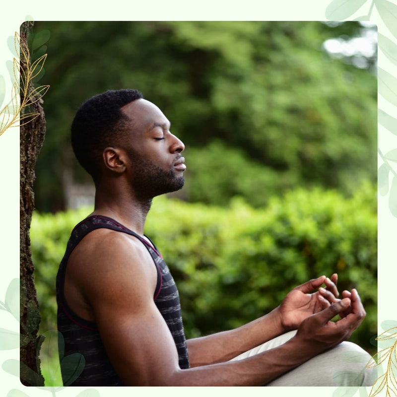 Man meditating outdoors with greenery in the background