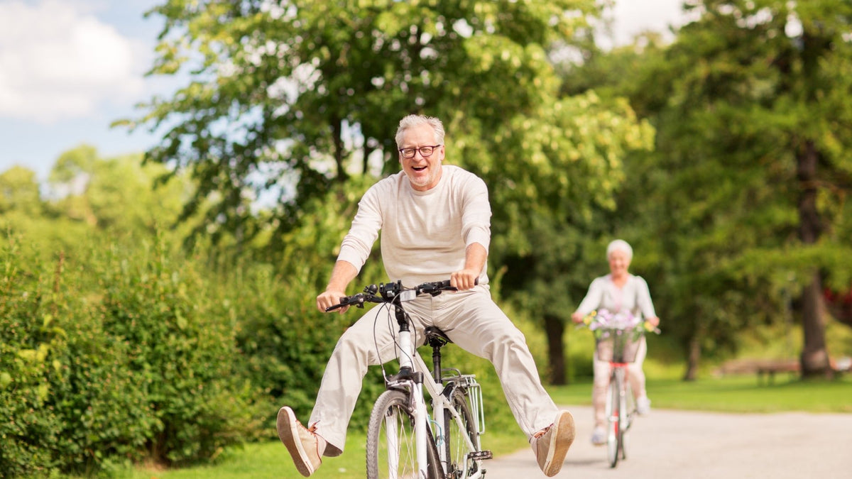 Older couple happily riding bicycles along a paved park path