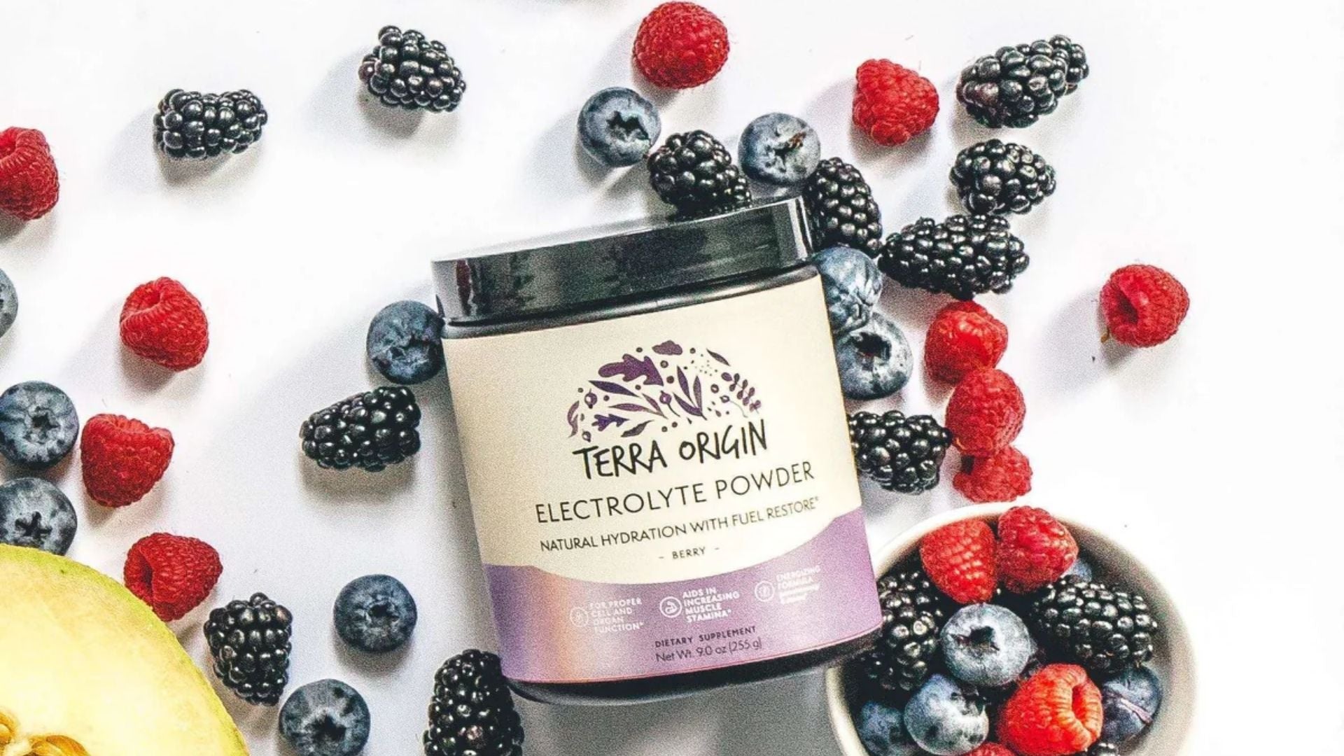 Terra Origin electrolyte powder container surrounded by berries on a white background